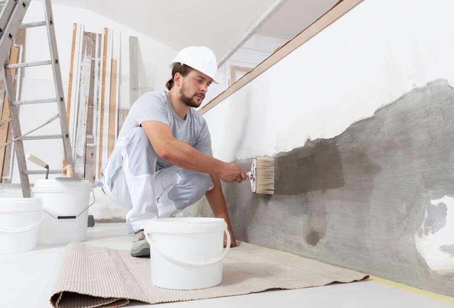 operaio dipinge parete casa